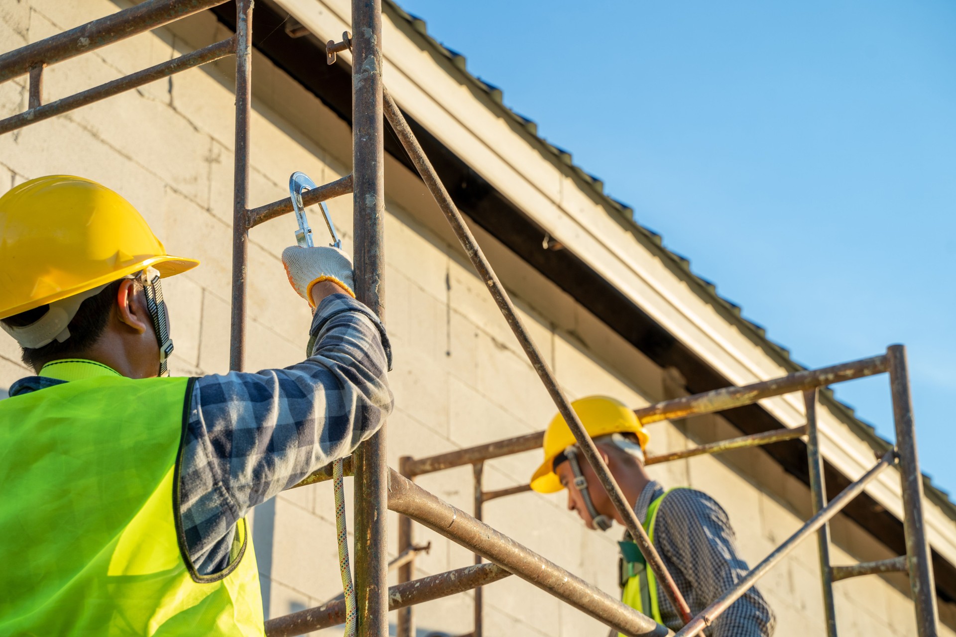 Construction workers in uniform and safety equipment working on scaffolding.