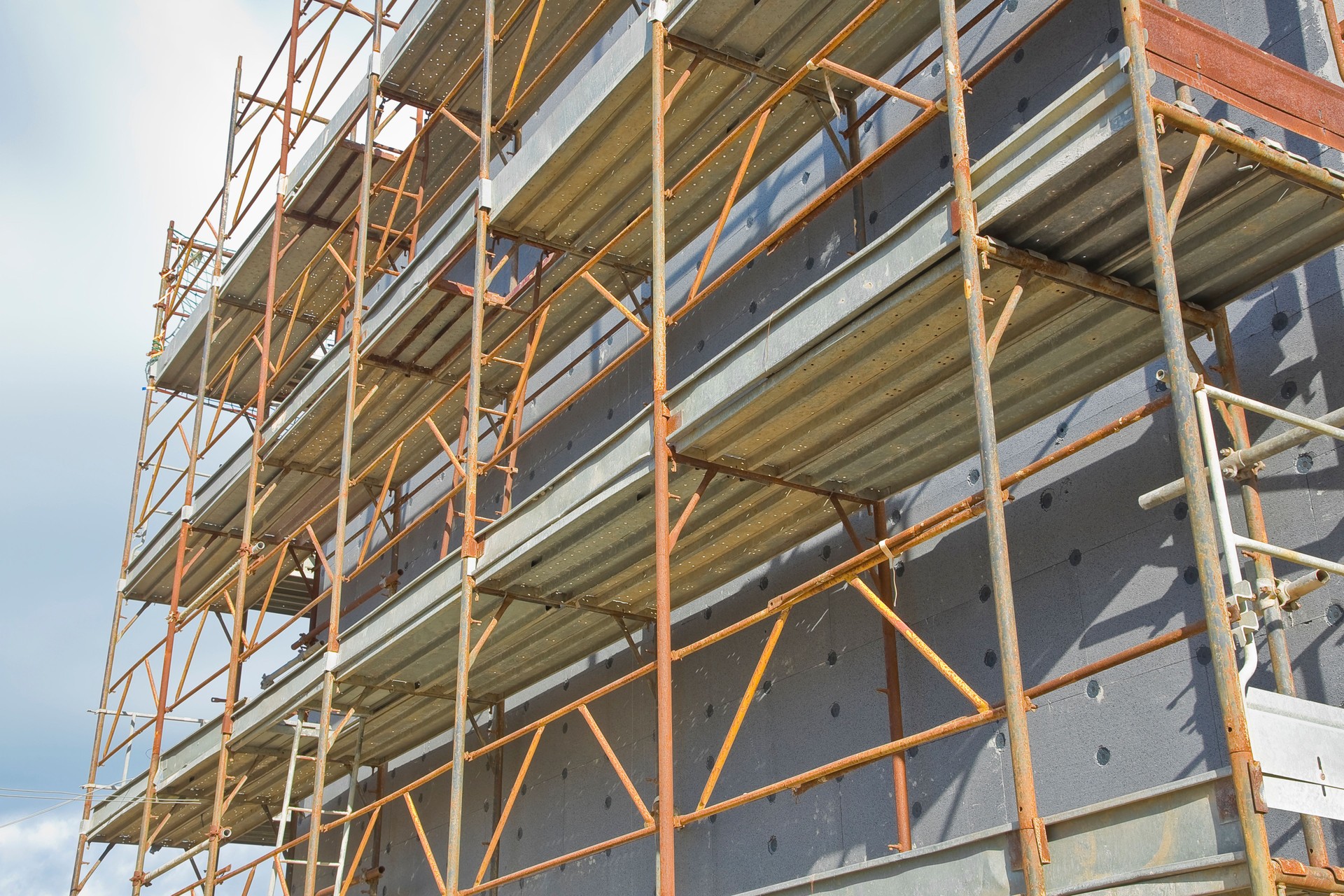 Metal scaffolding on a construction site for the construction of heat-insulating coatings to improve the energy efficiency of buildings